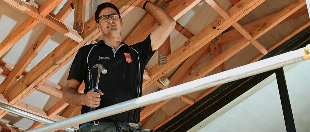 nzcb member builder working on roof trusses, giving a look of confidence in his work.